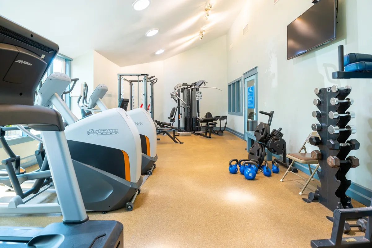 A modern, well-equipped fitness center featuring treadmills, weight machines, free weights, and kettlebells. The space is bright, organized, and encourages a healthy, active lifestyle.