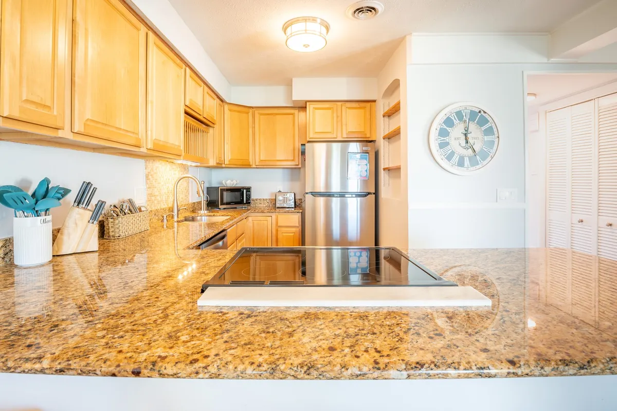 A modern kitchen with granite countertops, stainless steel appliances, and wood cabinetry. There's ample space for meal prep and entertaining, with sightlines that likely connect to the living and dining spaces, supporting a sense of community and conversation.