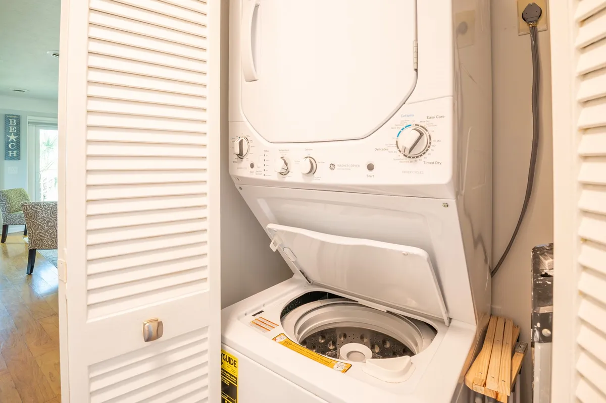 A compact laundry area featuring a stacked washer and dryer unit, tucked neatly within the interior. The space is bright and functional, demonstrating in-unit laundry convenience for guests.